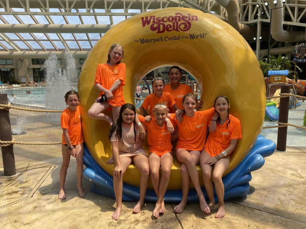 A picture of Summer Adventure Camp Senior campers sitting on a statue shaped like an innertube, all are smiling at the camera.